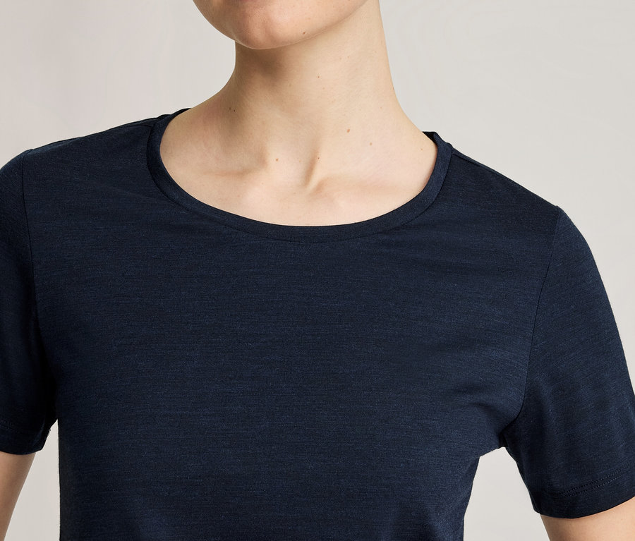 Zbliżenie osoby ubranej w granatowy T-shirt z krótkim rękawem i okrągłym dekoltem.