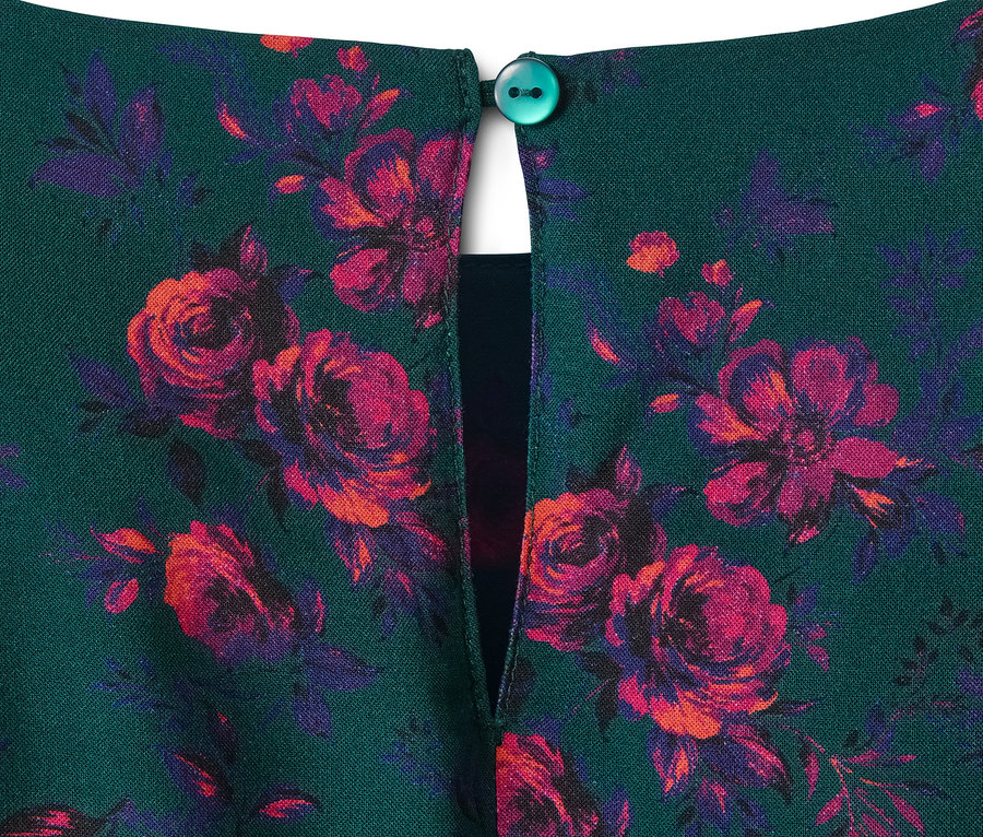 Detal sukienki z wiskozy z zielonym tłem i czerwono-fioletowymi kwiatami.