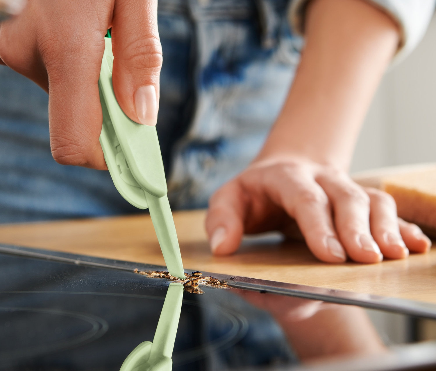 Kobieta czyści płytę ceramiczną szczotką wielofunkcyjną 3 w 1.