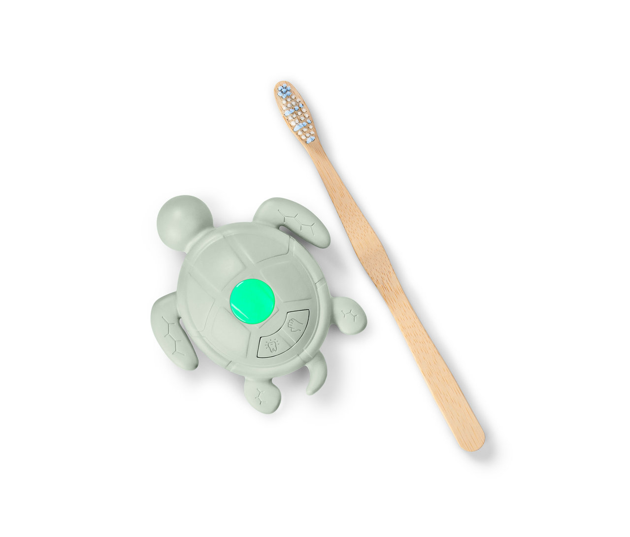 Żółw w kształcie minutnika do mycia rąk i szczotkowania zębów ze świecącym na zielono światełkiem oraz drewniana szczoteczka do zębów.