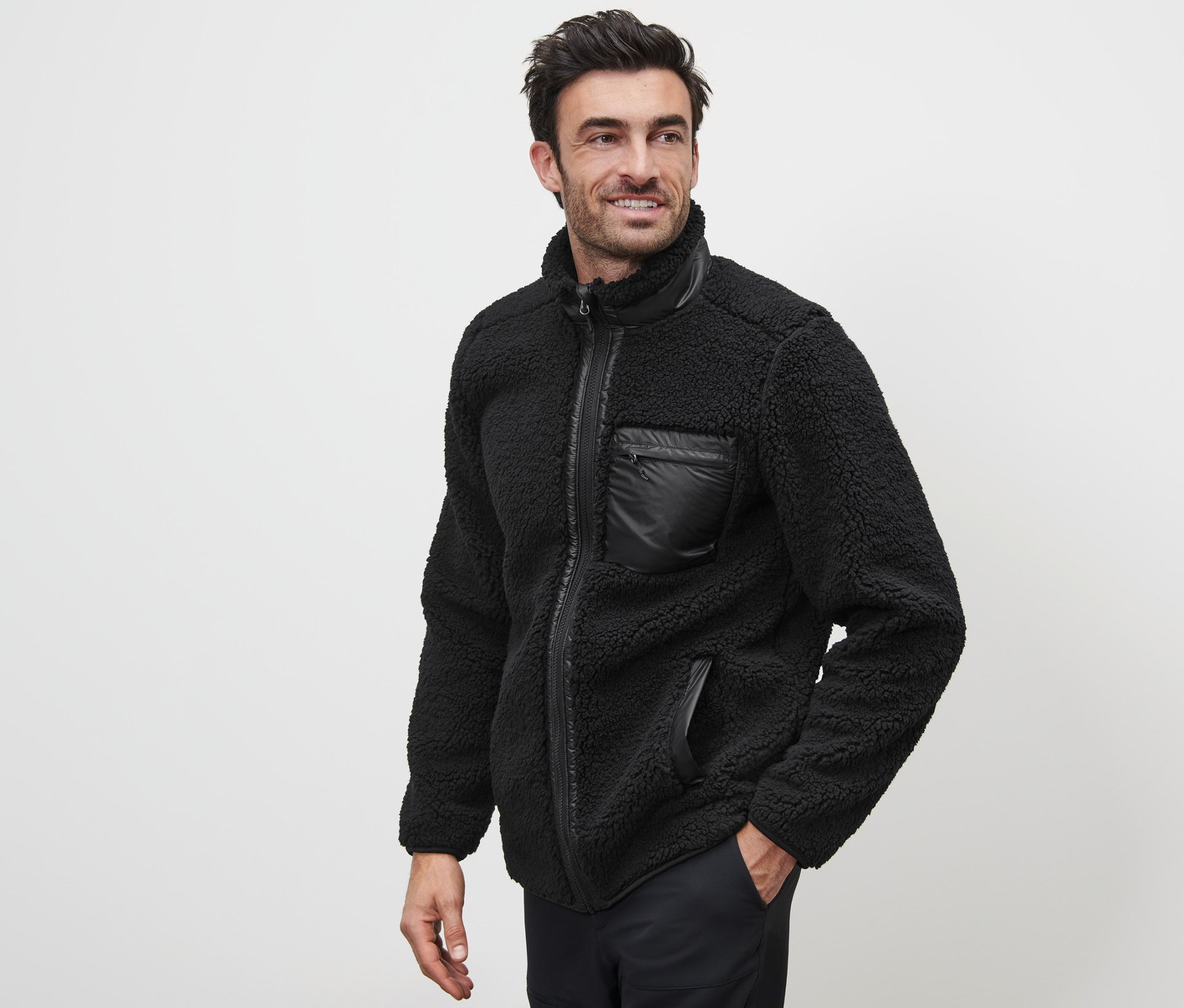 Uśmiechnięty mężczyzna pozuje w czarnej bluzie pluszowej.