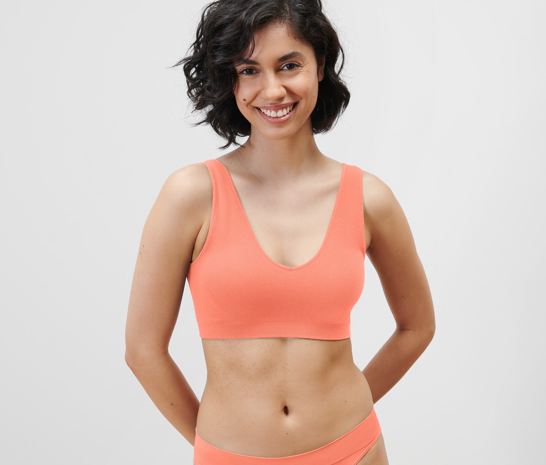 Uśmiechnięta kobieta ma na sobie bezszwową braletkę w kolorze papai.