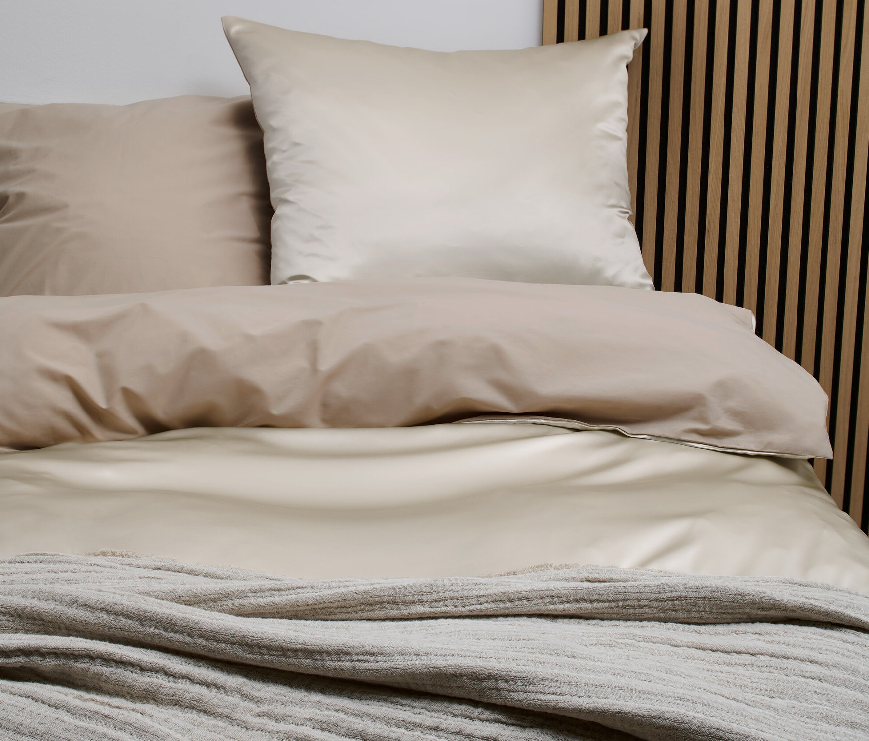 Pościel z jedwabiu i bawełny w standardowym rozmiarze leży na łóżku z drewnianym zagłówkiem.