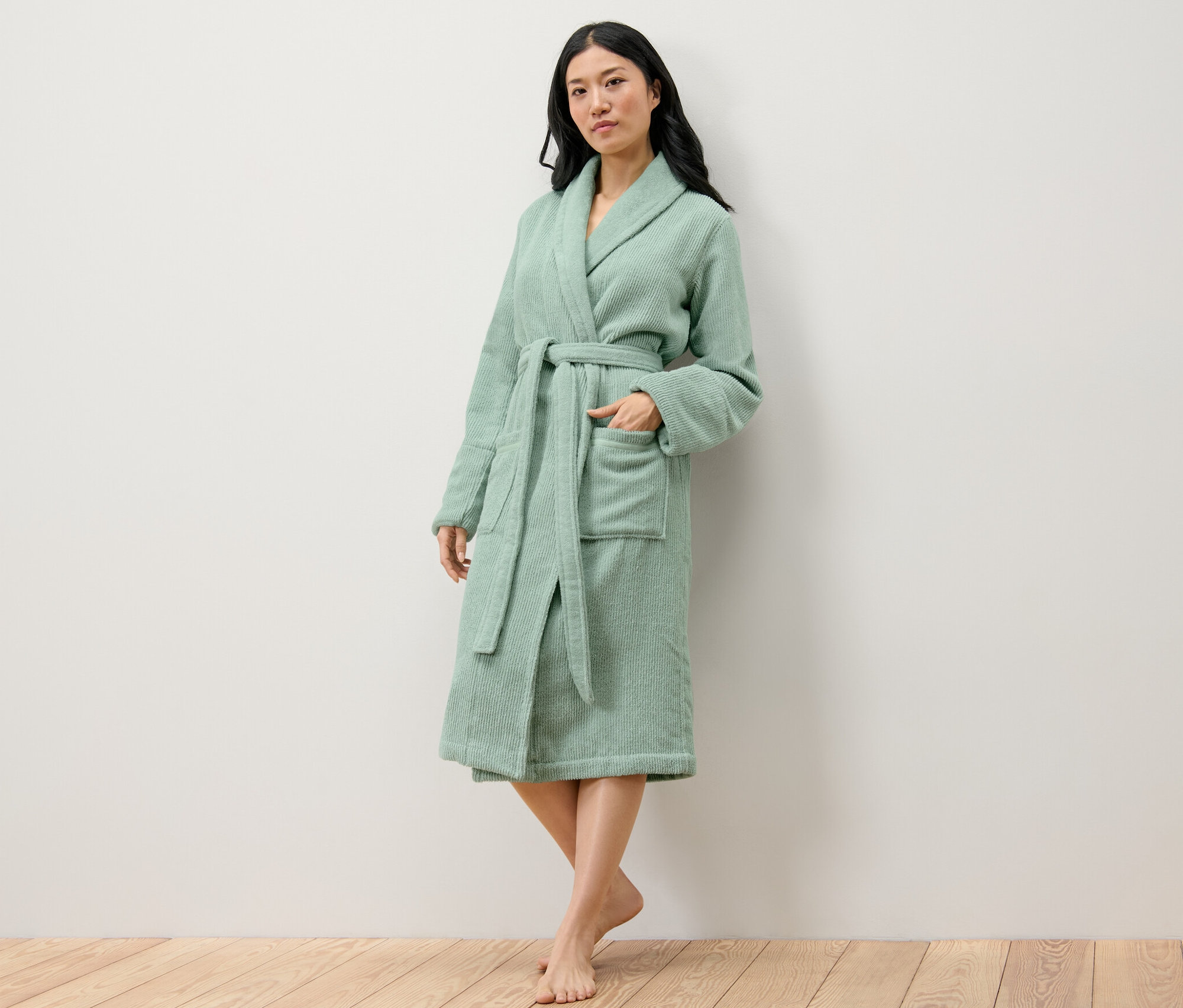 Kobieta pozuje w zielonym szlafroku damskim.