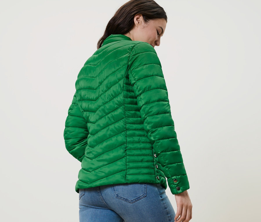 Kobieta ma na sobie pikowaną kurtkę i dżinsy.