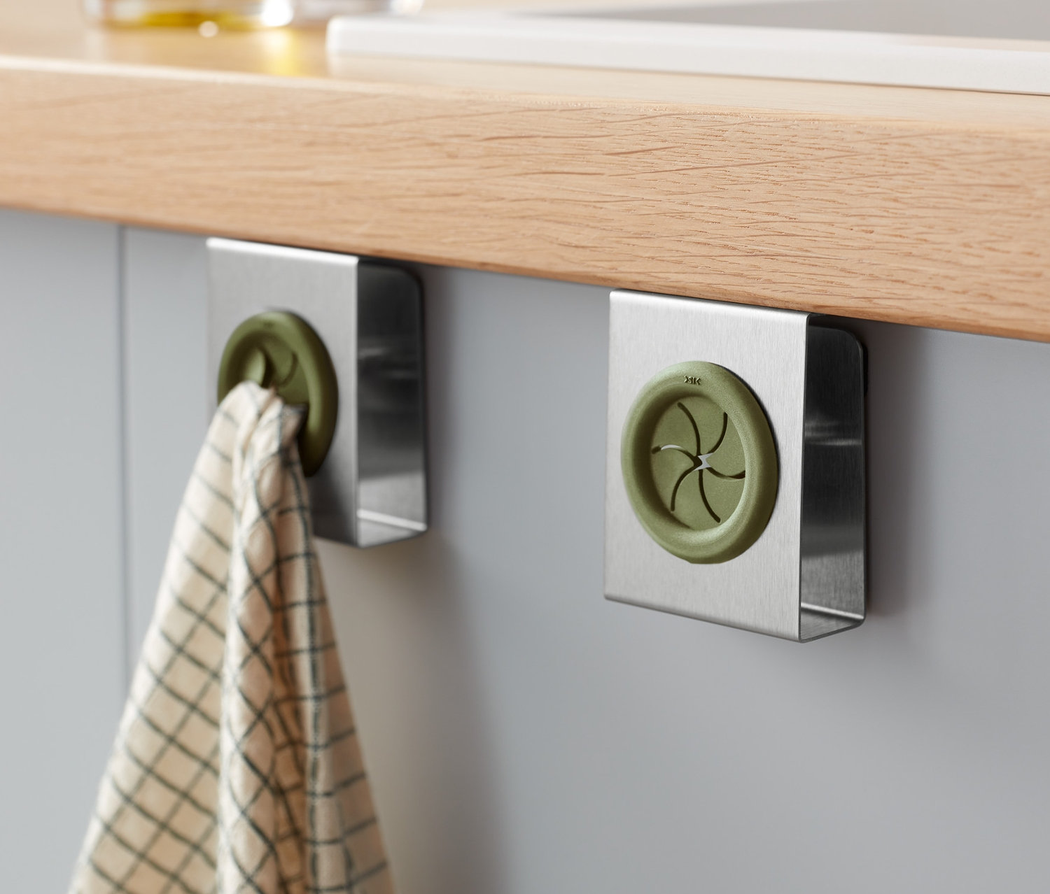 Dwa uchwyty na ścierki do wycierania naczyń przymocowane do blatu kuchennego.