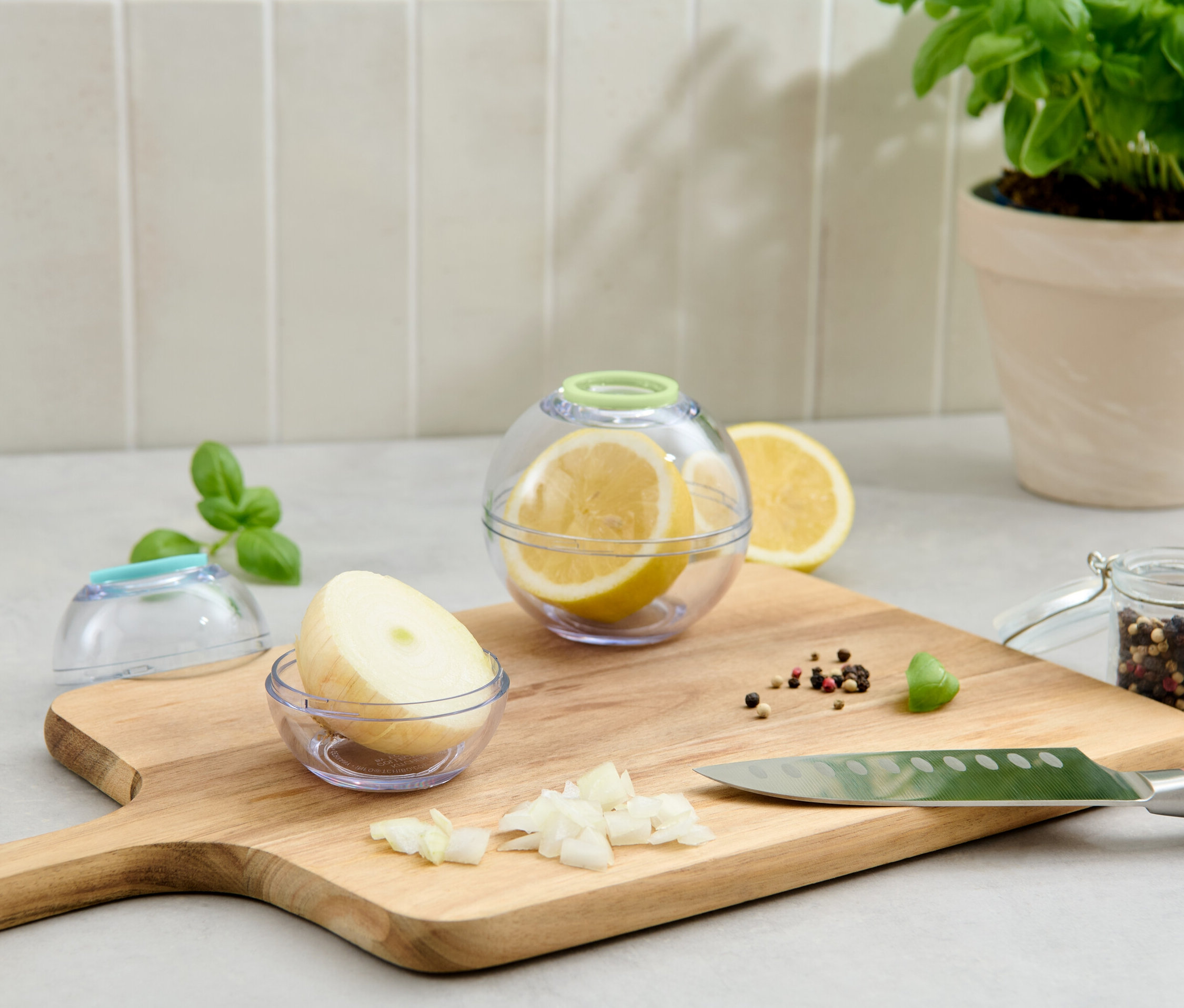 Dwa pojemniki spożywcze: w jednym cytryna, w drugim cebula, leżą na desce do krojenia.