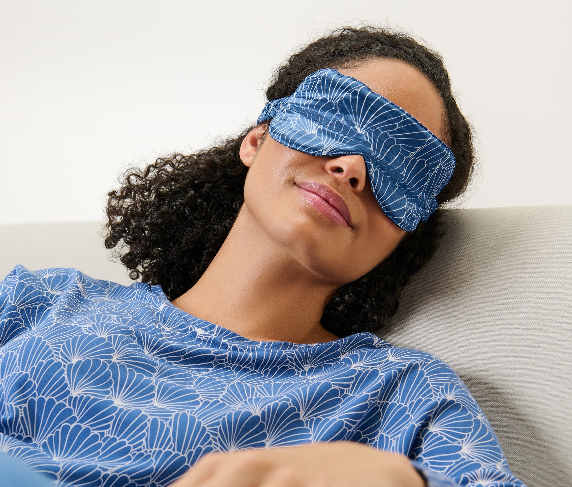 Kobieta leży w jedwabnej masce do spania na oczach.
