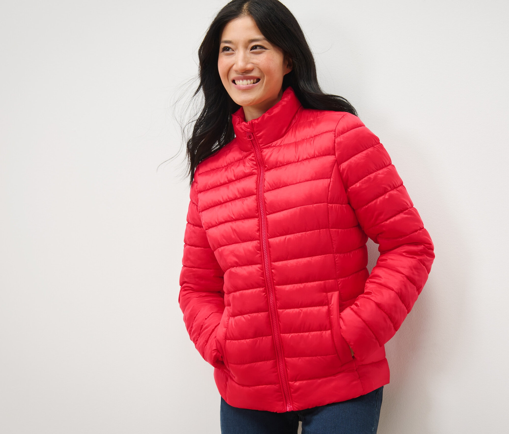 Uśmiechnięta kobieta pozuje w czerwonej pikowanej kurtce.