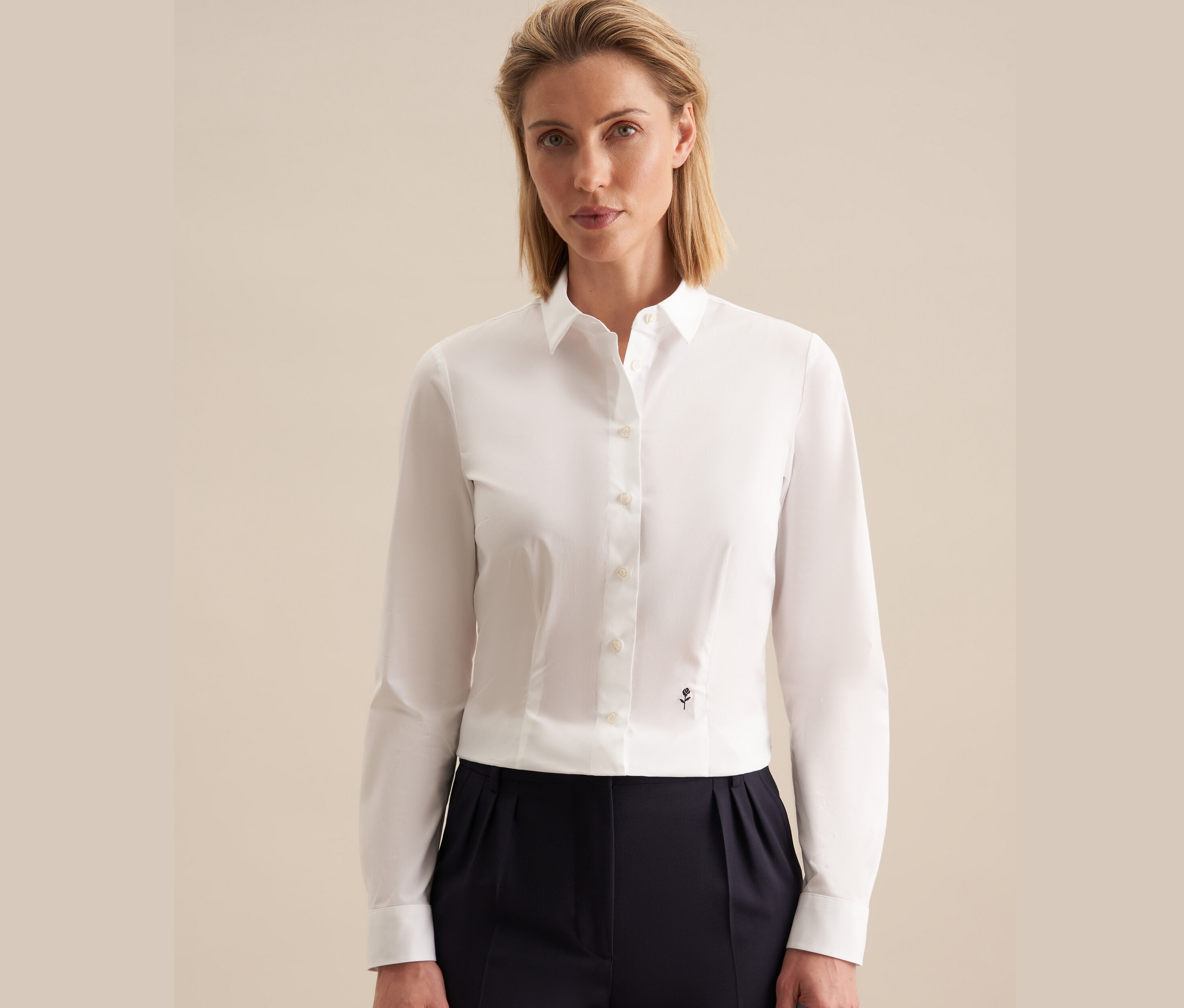 Kobieta ma na sobie białą koszulę slim fit Seidensticker i granatowe spodnie.