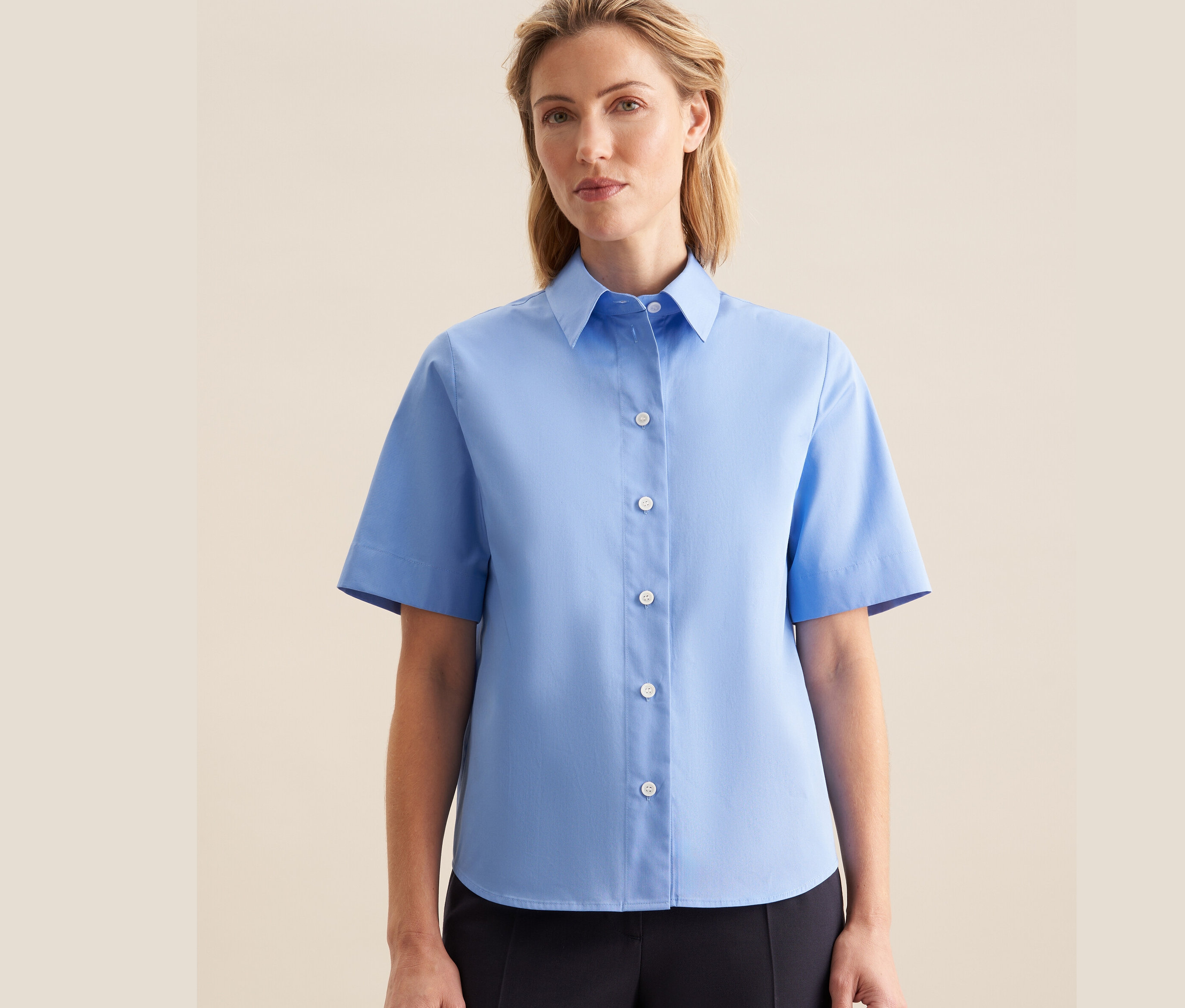 Kobieta ma na sobie jasnoniebieską koszulę z krótkim rękawem Seidensticker.