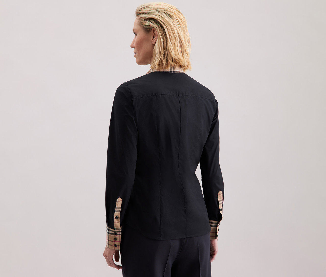 Kobieta ma na sobie popelinową bluzkę z detalami w kratę marki Seidensticker.