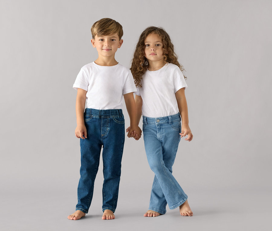 Chłopiec i dziewczynka trzymają się za ręce, oboje w białych T-shirtach i spodniach na gumce – fason „Luca”.