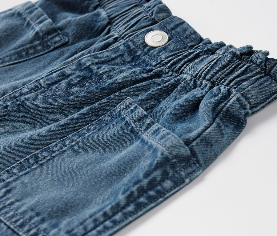 Zbliżenie na dżinsowe szorty dziecięce z elastycznym pasem i kieszeniami.