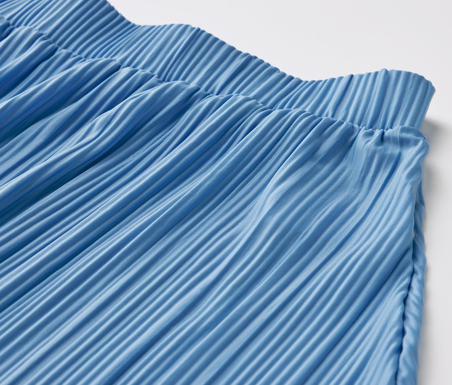 Zbliżenie na niebieską spódnicę plisowaną.
