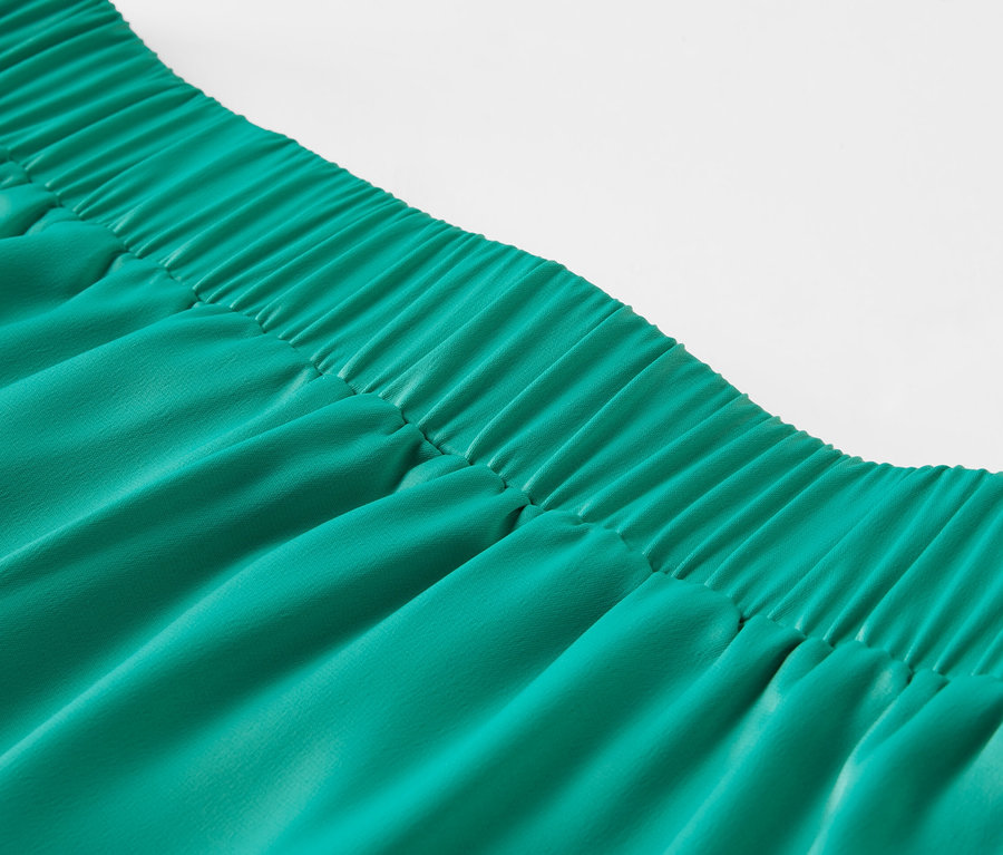 Zbliżenie na zieloną spódnicę z satyny z elastycznym pasem.