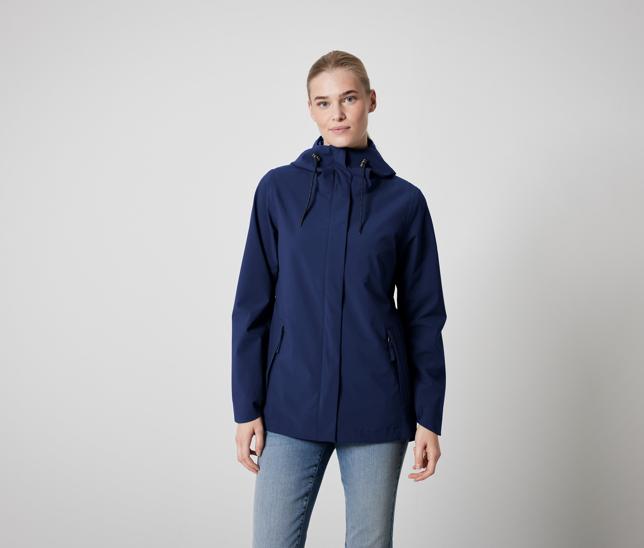 Kobieta ma na sobie niebieską kurtkę i dżinsy.