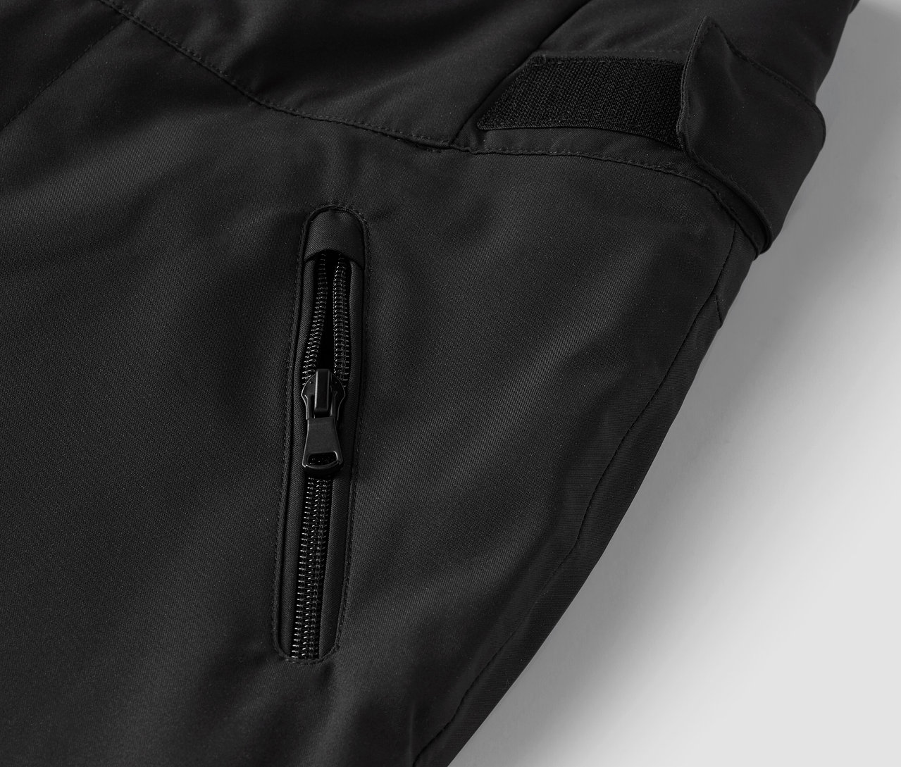 Szczegół czarnych spodni z kieszenią na zamek błyskawiczny.