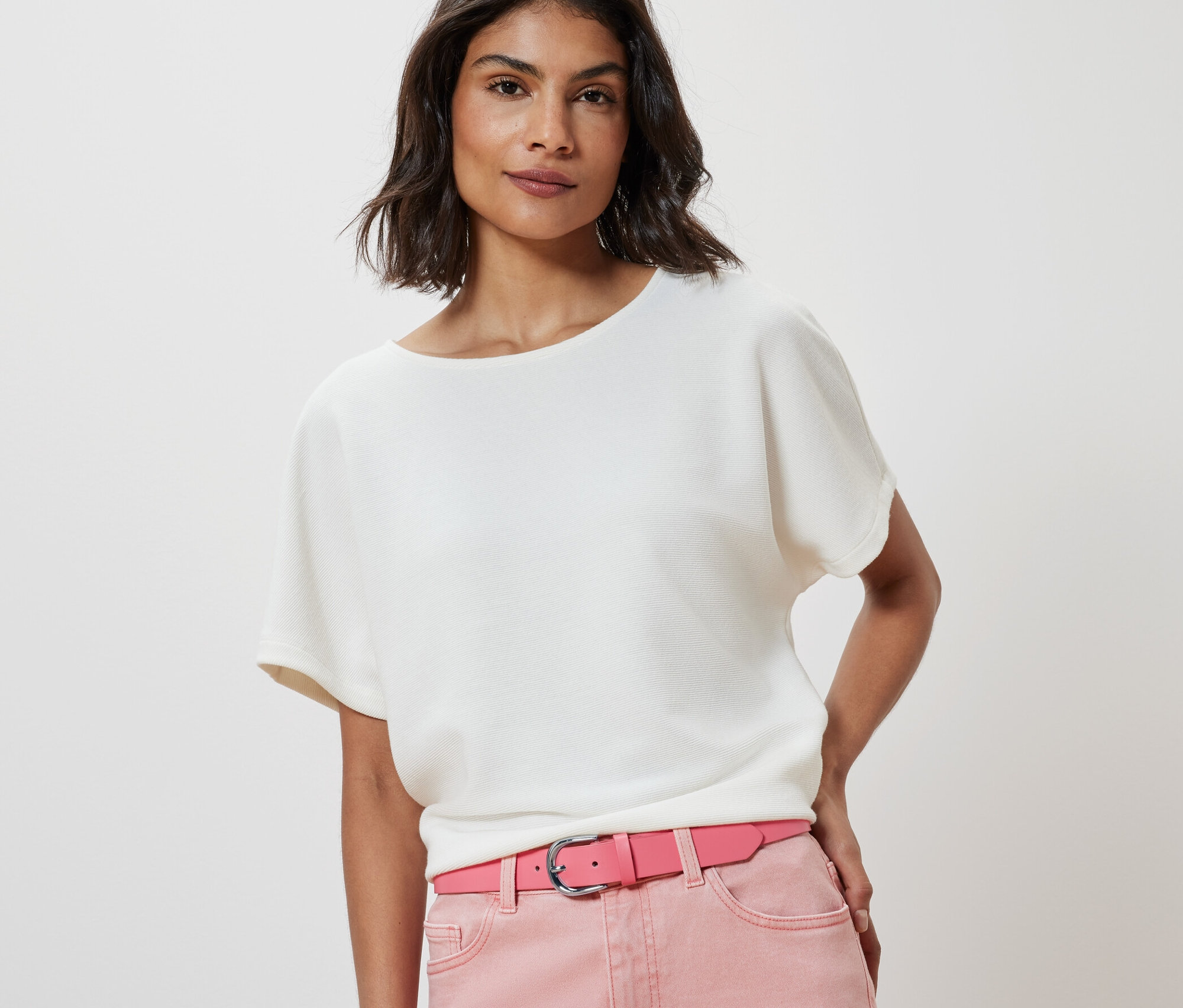 Kobieta ma na sobie białą bluzkę i różowy pasek.