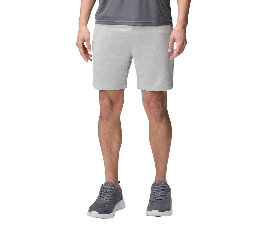 Mężczyzna w szarych szortach i szarych butach sportowych Fila.