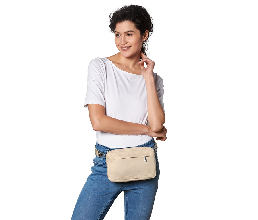 Kobieta pozuje z beżową torbą na ramię z zabezpieczonym paskiem.