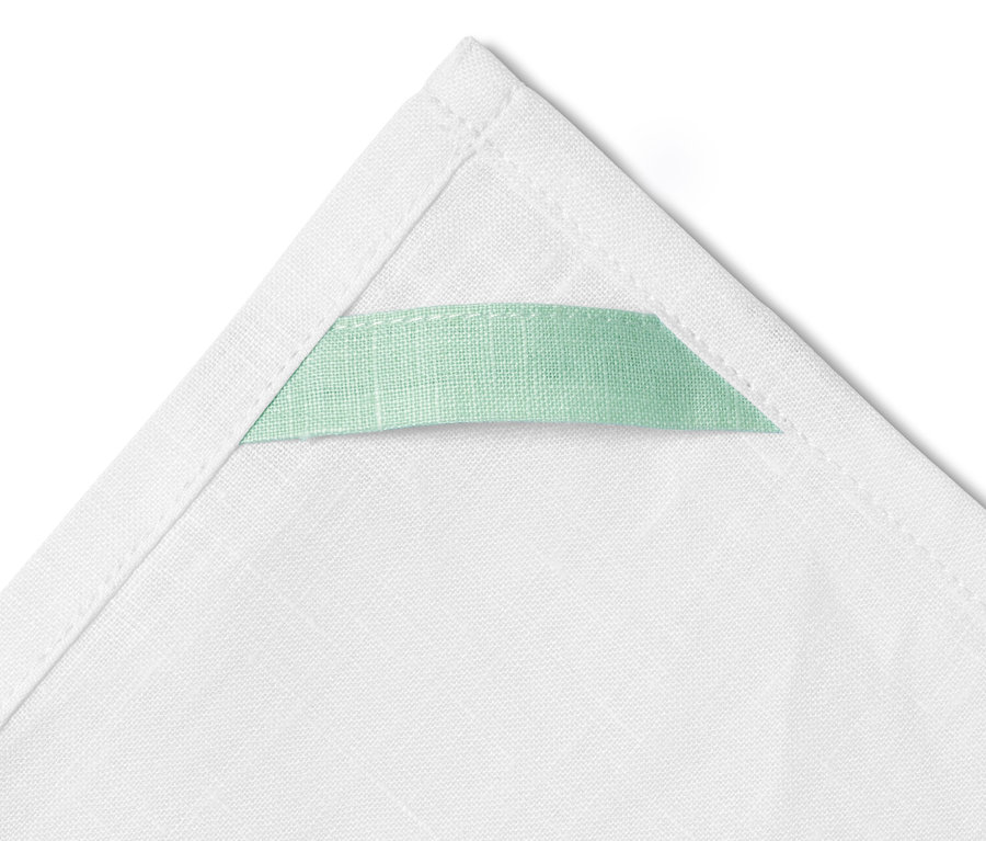 Zbliżenie na białą lnianą ściereczkę z jasnozieloną pętelką.