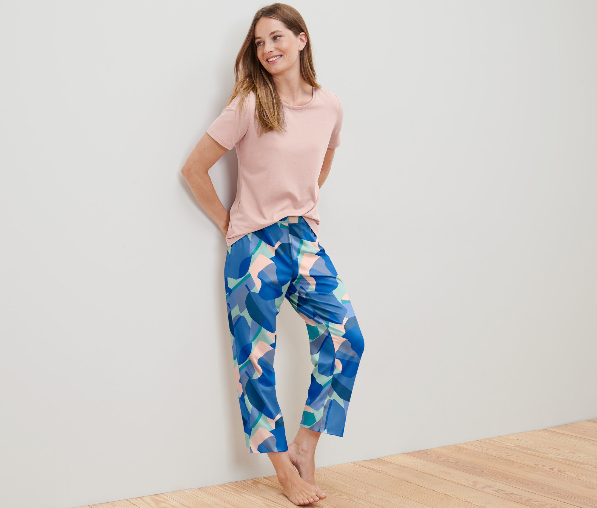 Kobieta opiera się o ścianę w piżamie.