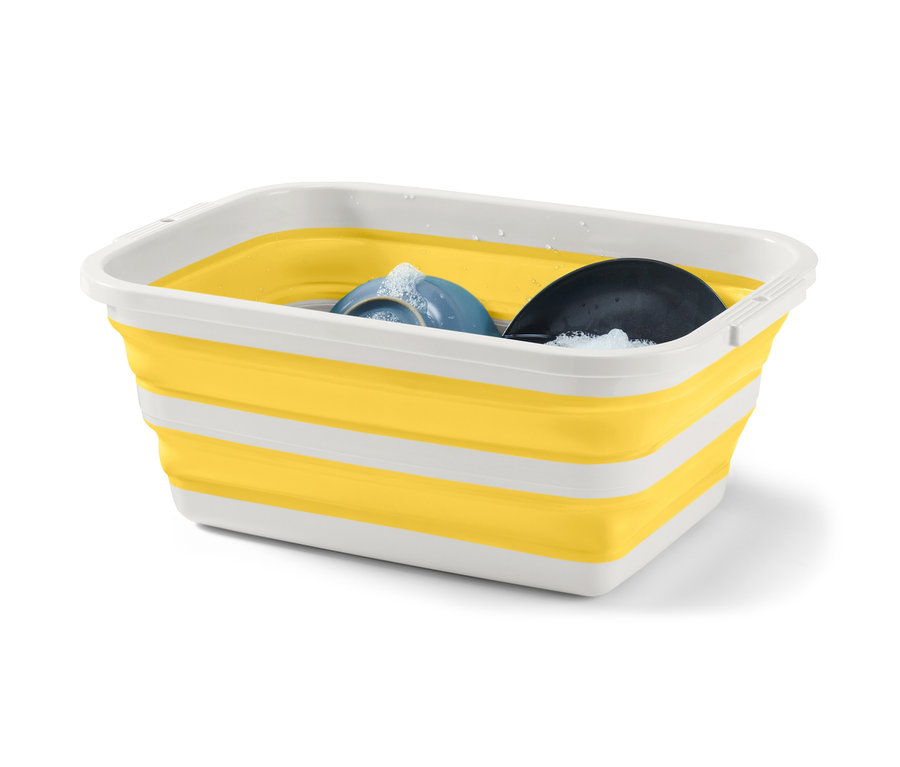 Składany kosz na pranie w kolorze żółto-białym z płynem do naczyń i naczyniami w środku.