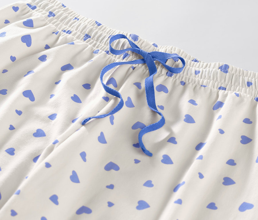 Zbliżenie na spodnie od piżamy w serduszka z niebieskim sznurkiem.