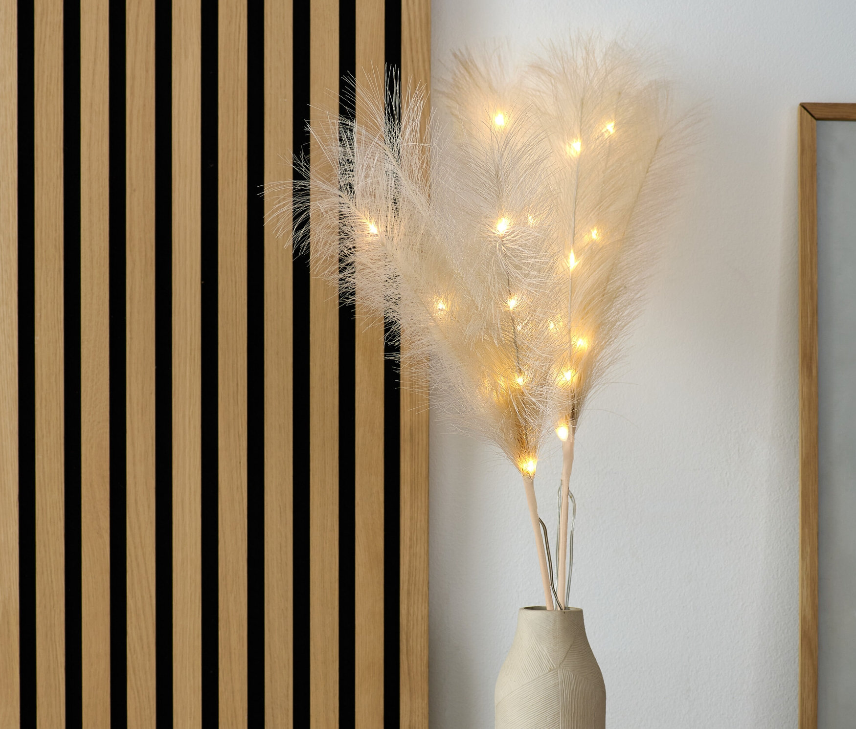 Dekoracyjne gałązki LED „Trawa ozdobna” w wazonie na komodzie.