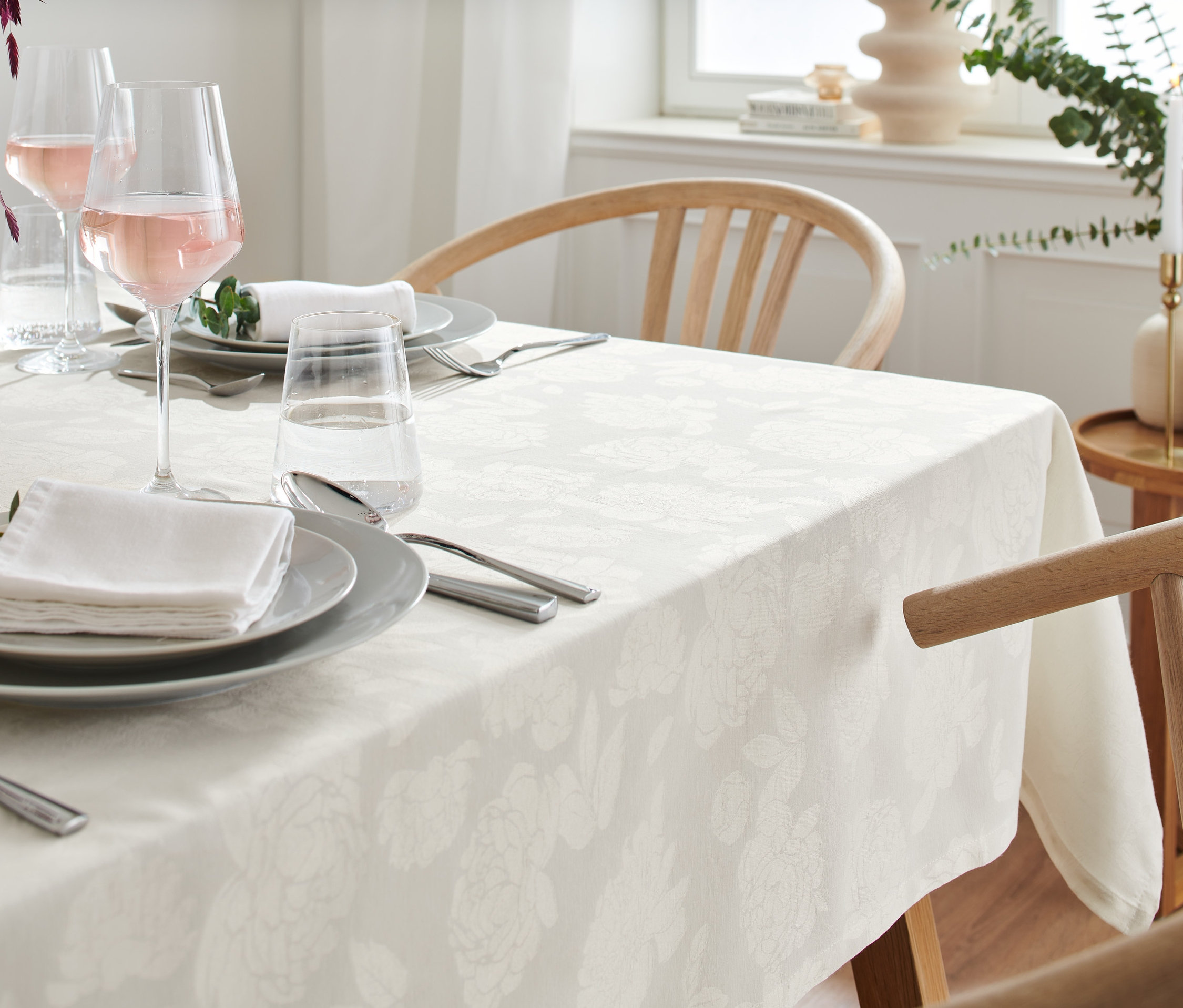 Nakryty stół z obrusem żakardowym o wymiarach 145 x 255 cm i obrusem żakardowym o standardowej wielkości 140 x 180 cm.