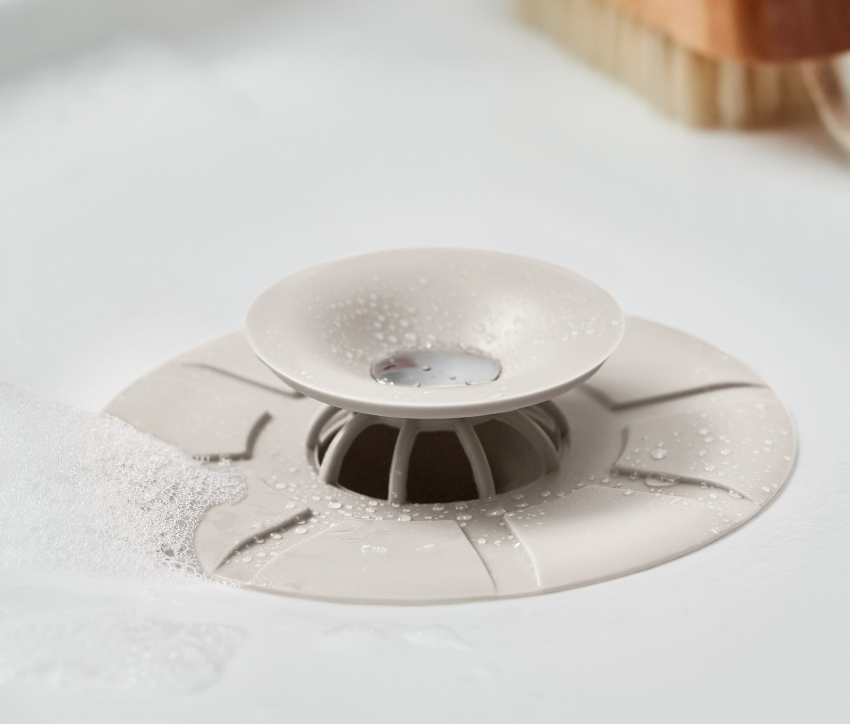 Zbliżenie sitka i korka do odpływu w umywalce z bąbelkami.