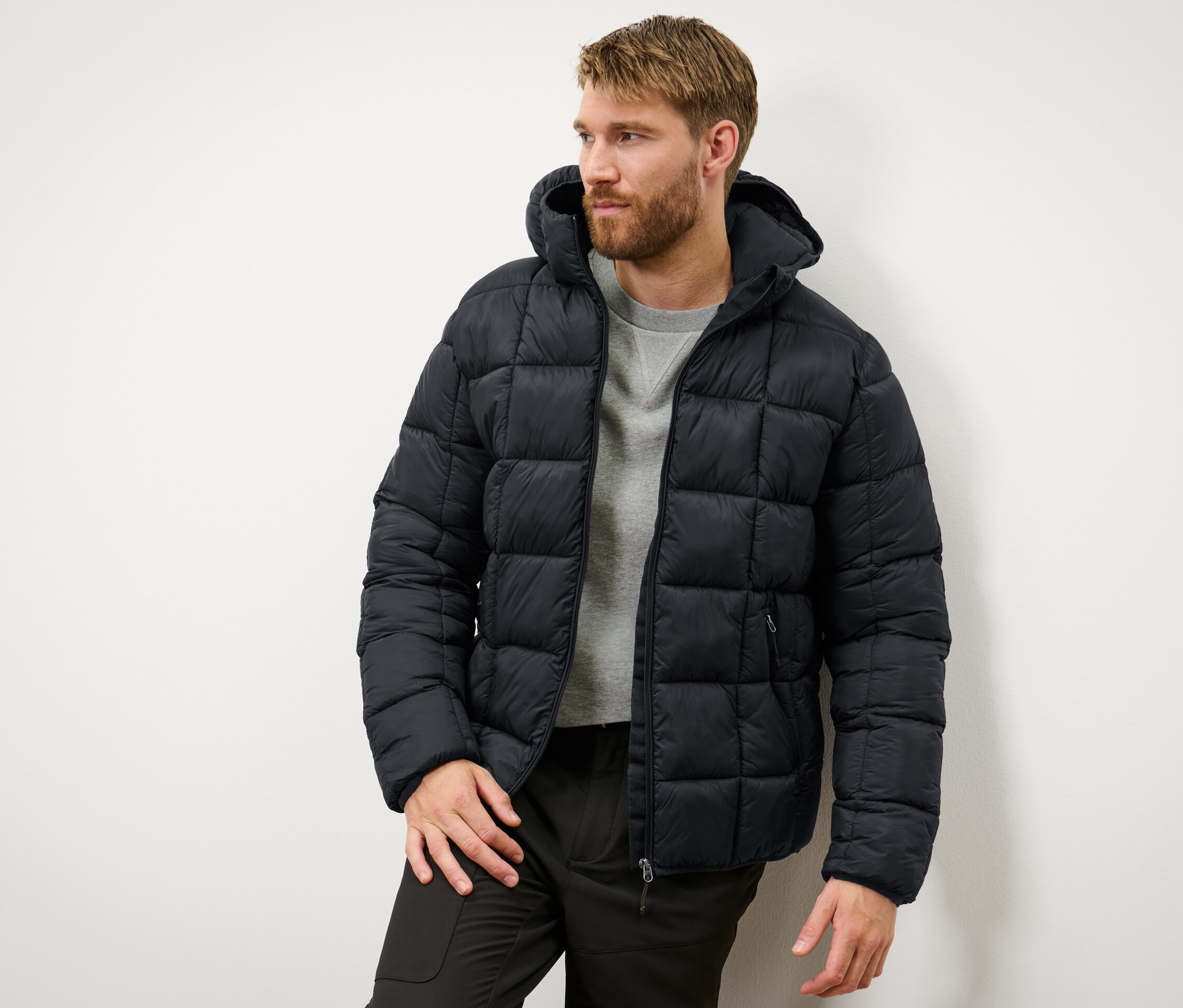 Mężczyzna ma na sobie czarną kurtkę pikowaną.
