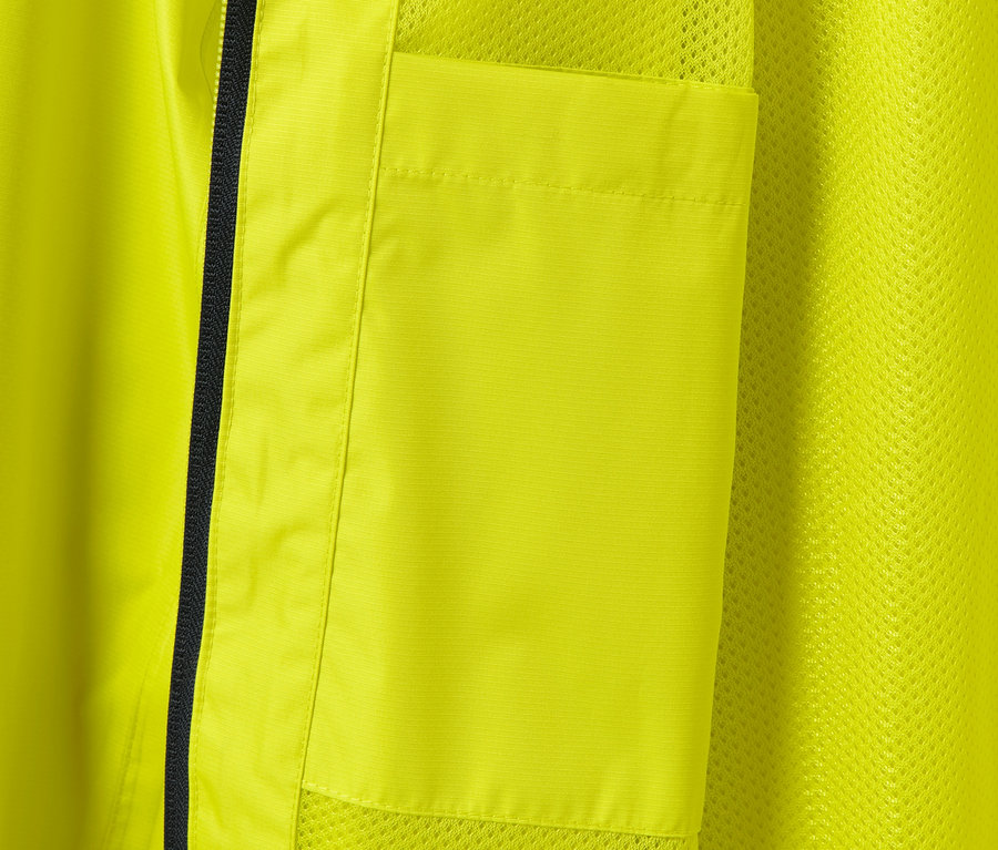 Szczegół żółtej kurtki przeciwdeszczowej z kieszenią i czarnym zamkiem błyskawicznym.