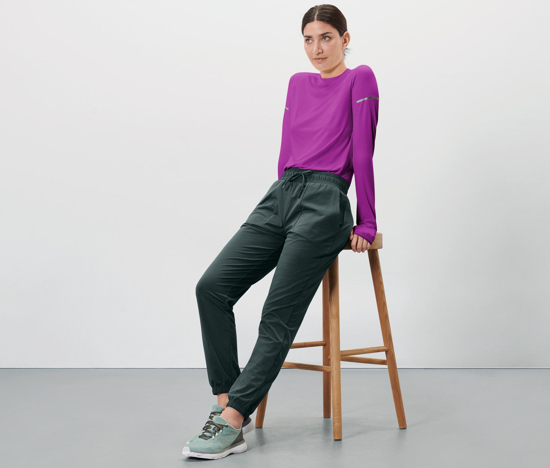 Kobieta siedzi na stołku, ubrana w termoaktywne spodnie funkcyjne.