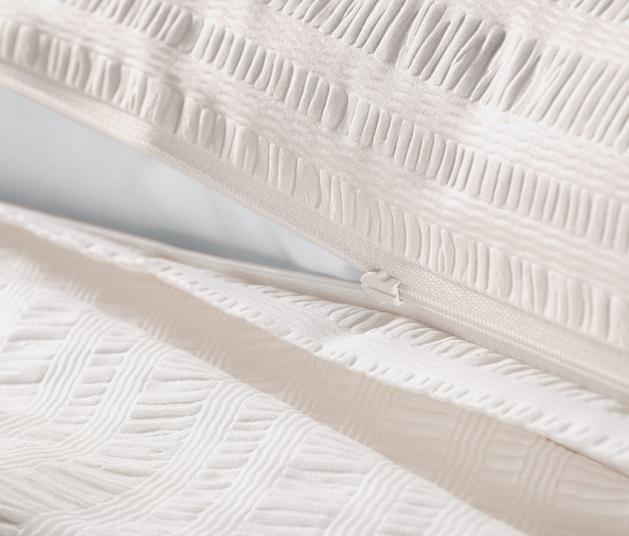 Zbliżenie na złamaną biel pościeli z kory w rozmiarach standardowym i niestandardowym z zamkiem błyskawicznym.