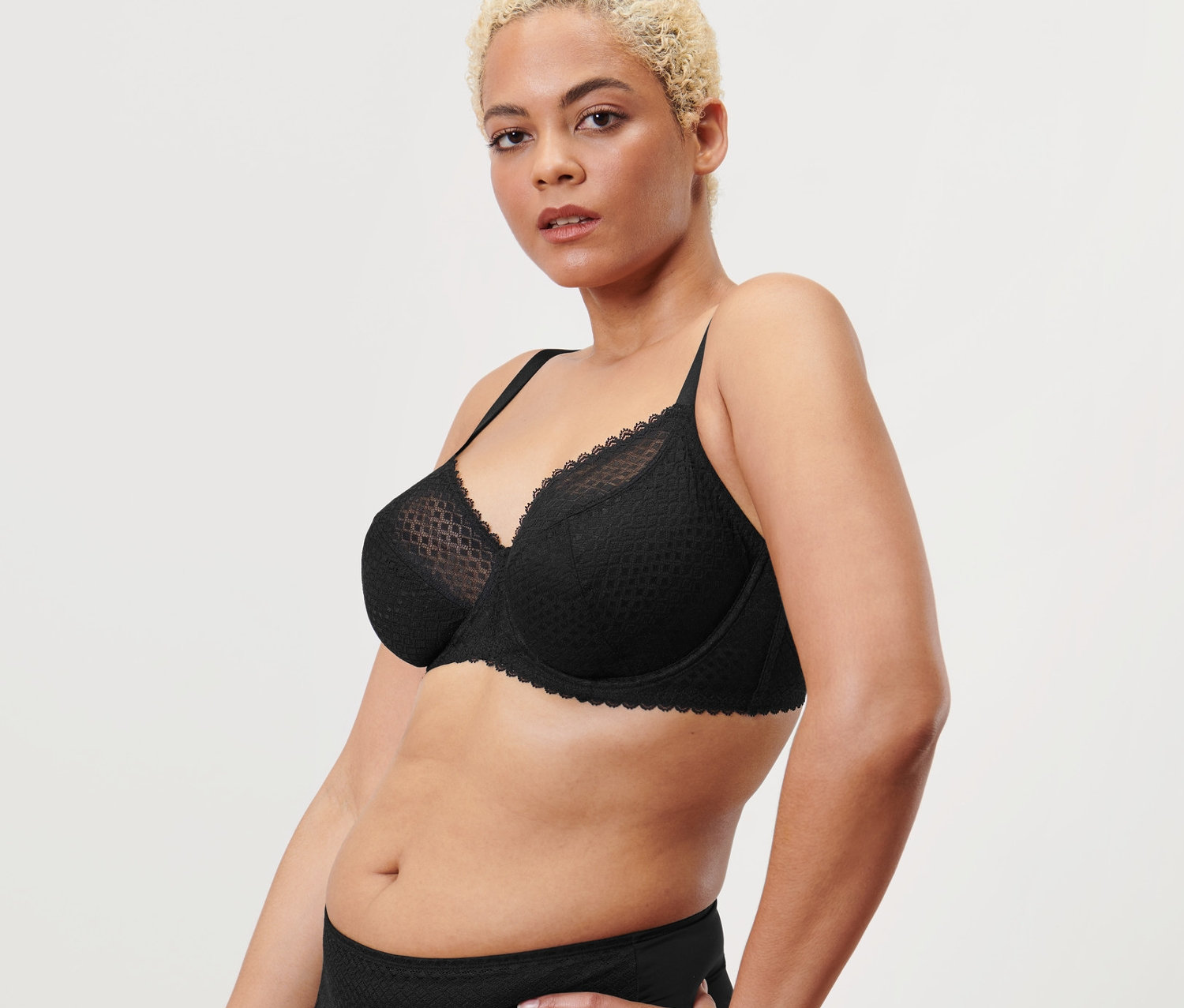 Kobieta pozuje w czarnym biustonoszu na fiszbinach.