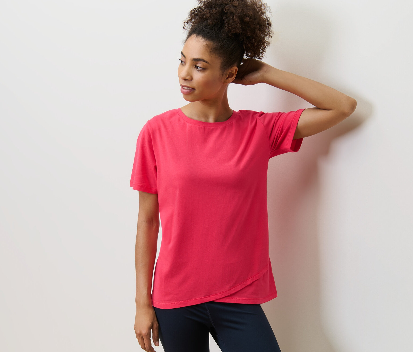 Kobieta pozuje w koszulce sportowej.