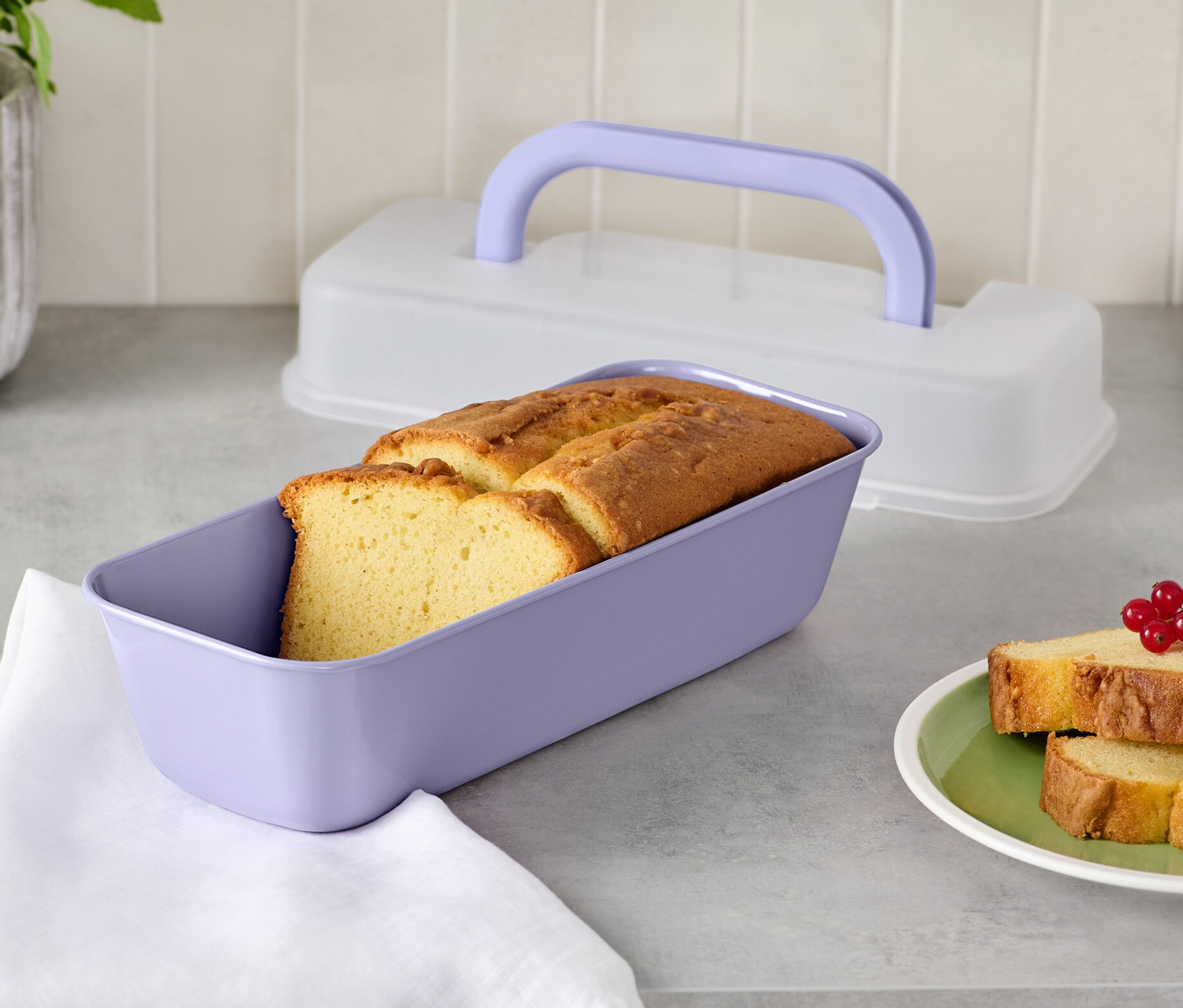 Chleb w fioletowej formie do pieczenia z pokrywką i dwie kromki chleba na talerzu.