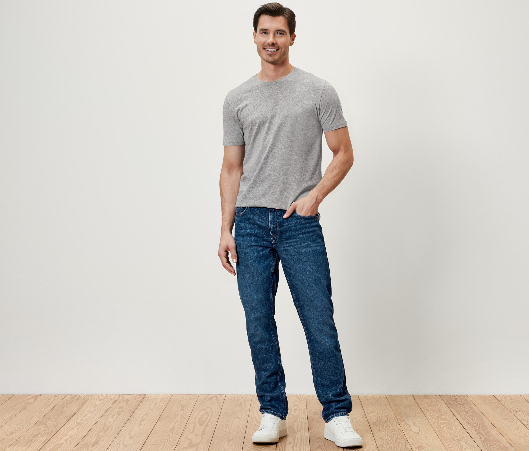 Mężczyzna stoi i ma na sobie spodnie dżinsowe.