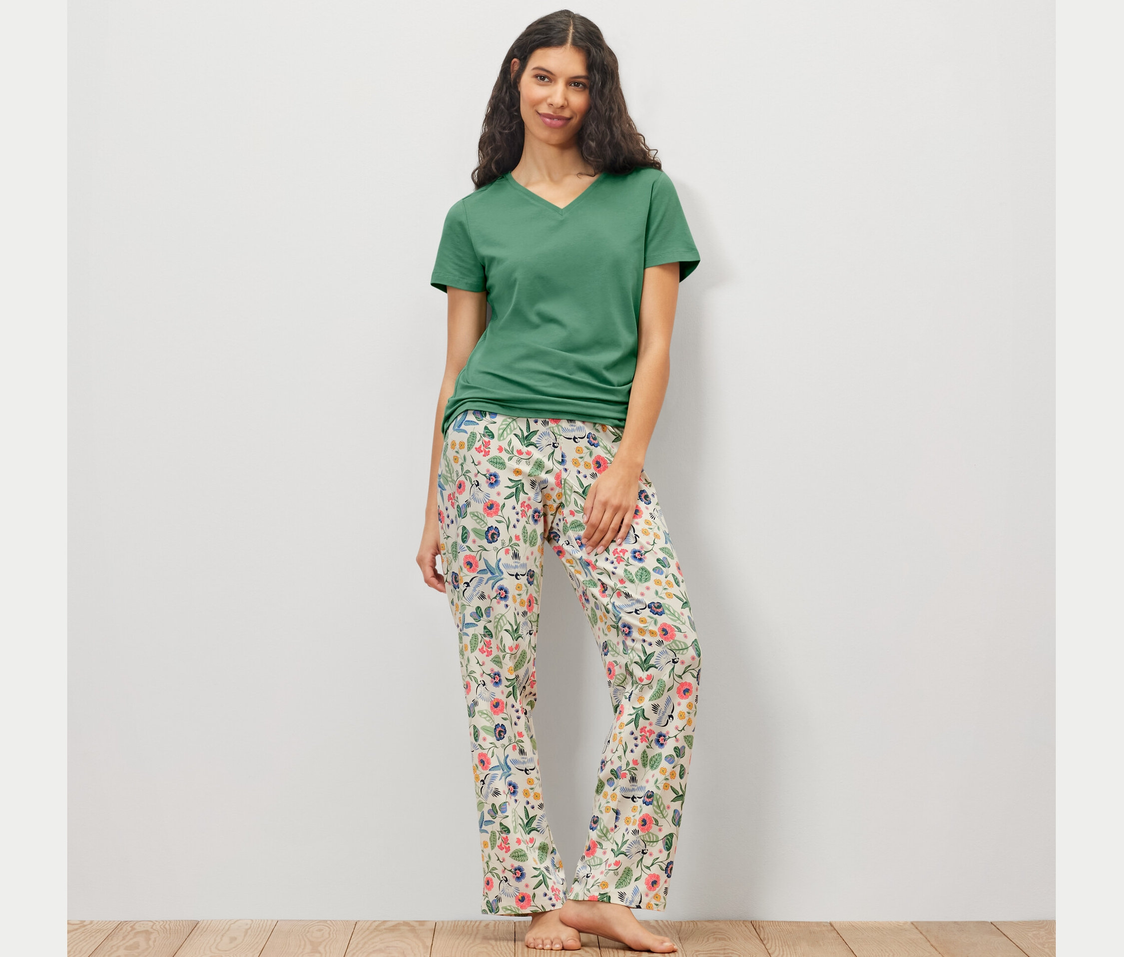 Kobieta w piżamie z kwiecistymi spodniami i zielonym T-shirtem.