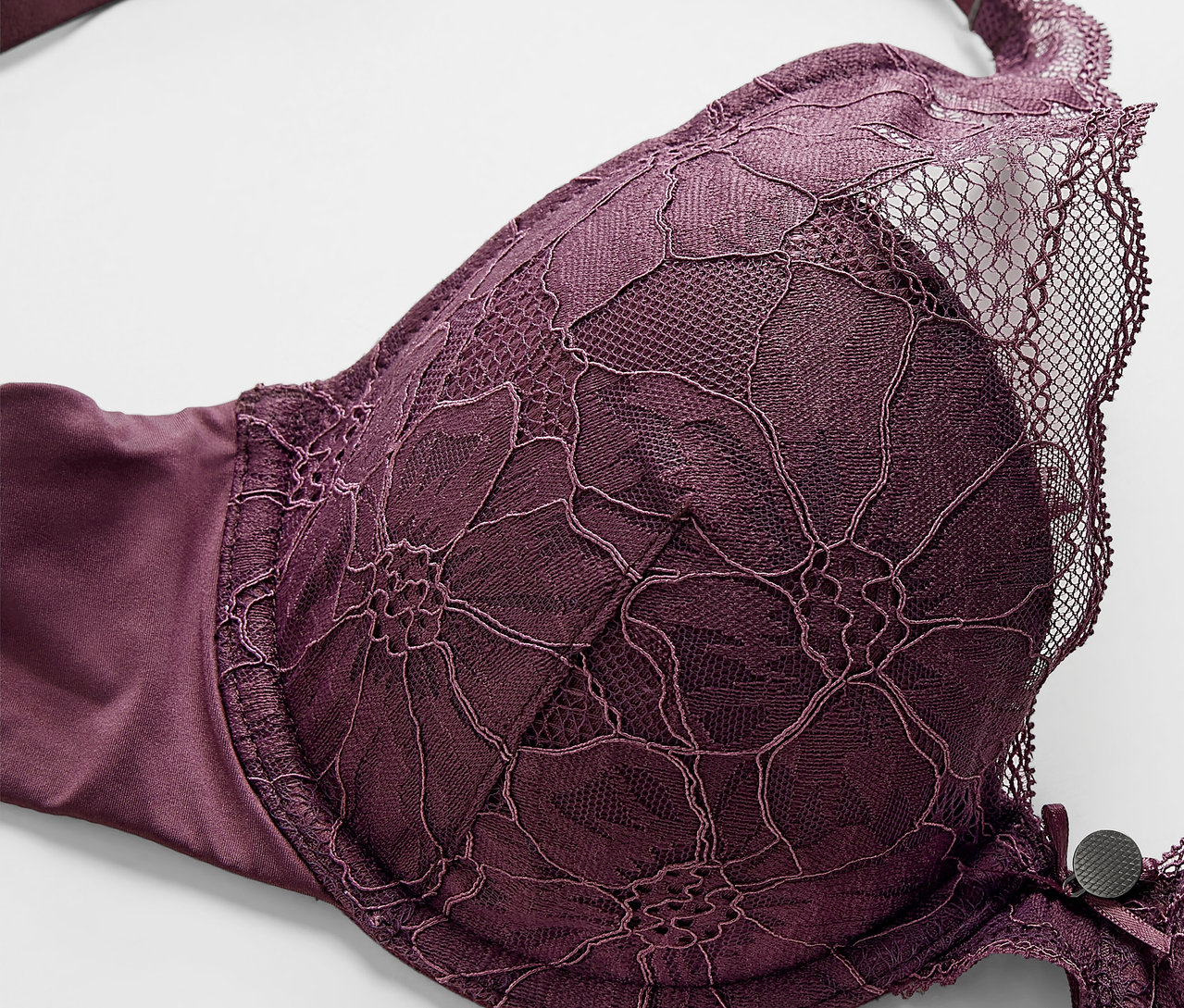 Zbliżenie fioletowego biustonosza z modelowanymi miseczkami i kwiatową koronką.