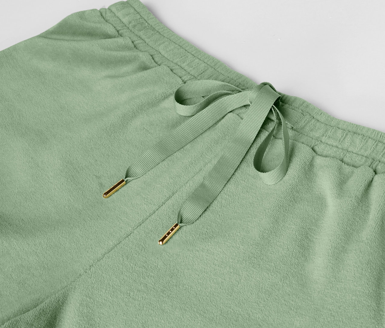 Zdjęcie detalu jasnozielonych spodni dresowych ze sznurkiem.