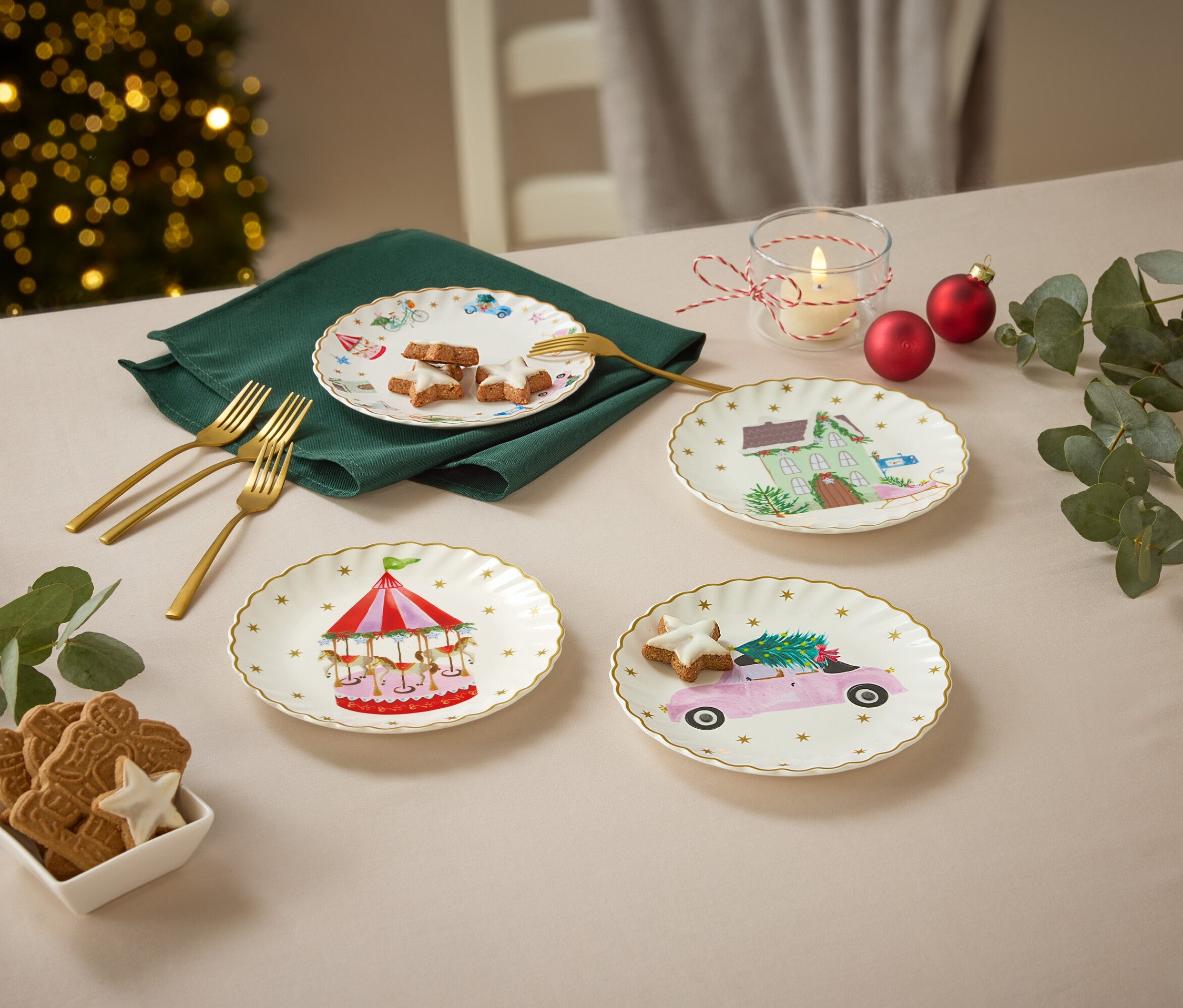 Cztery talerze z motywami świątecznymi na stole z dekoracjami świątecznymi.