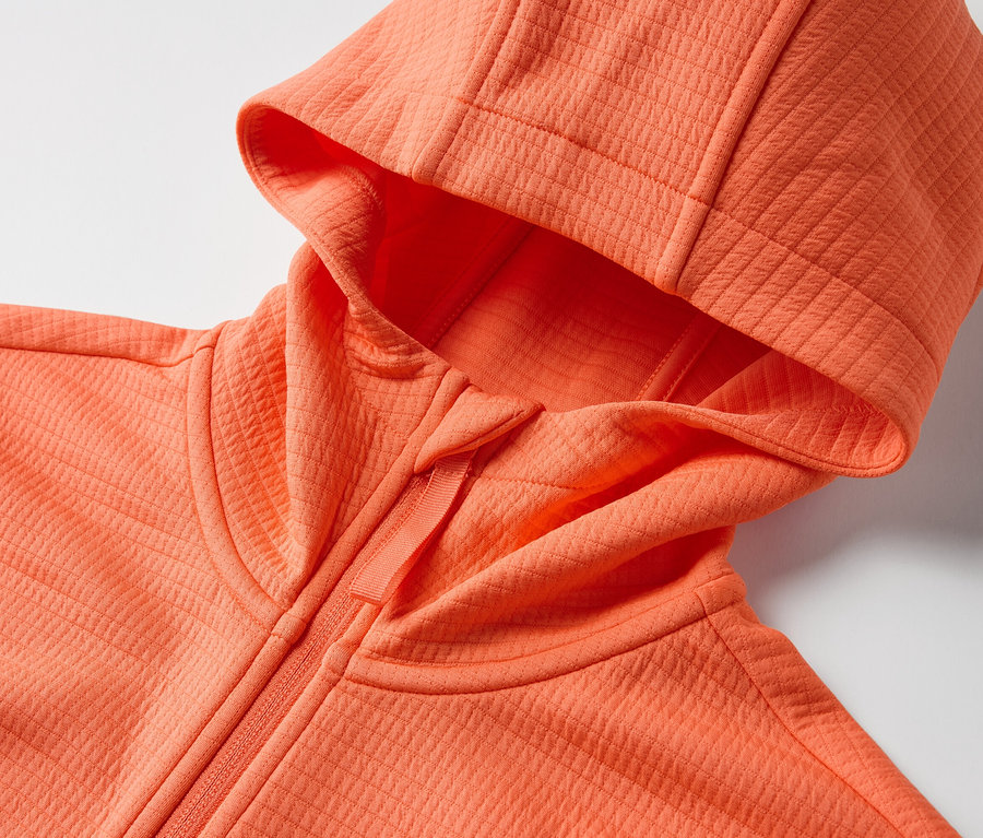 Zbliżenie na pomarańczową bluzę funkcyjną z kapturem.