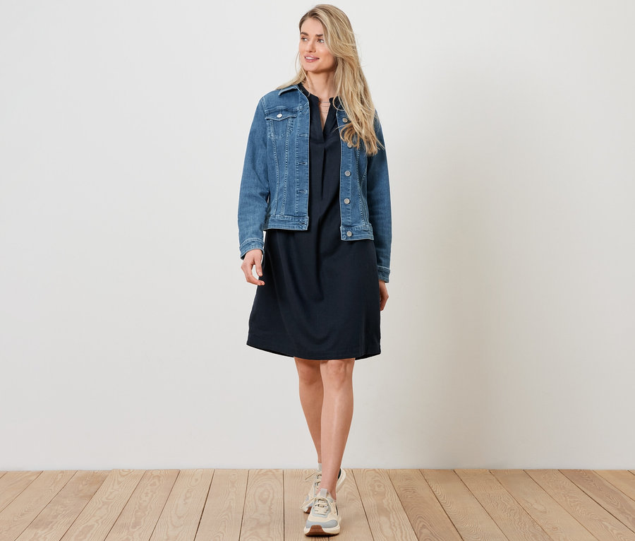 Kobieta ma na sobie kurtkę dżinsową i sukienkę lnianą.