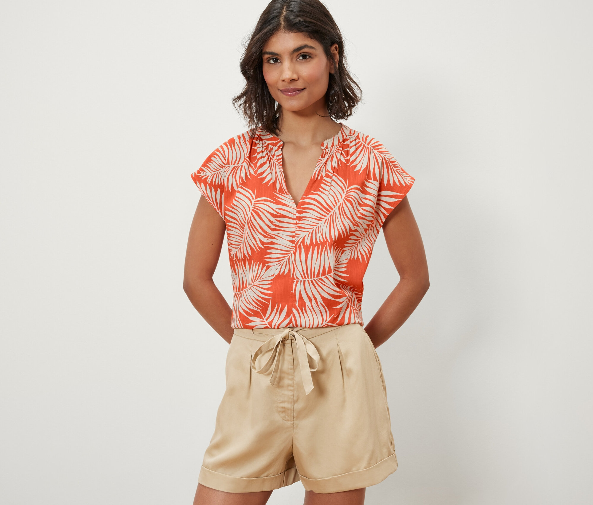 Kobieta ma na sobie pomarańczową wzorzystą bluzkę z krótkim rękawem.