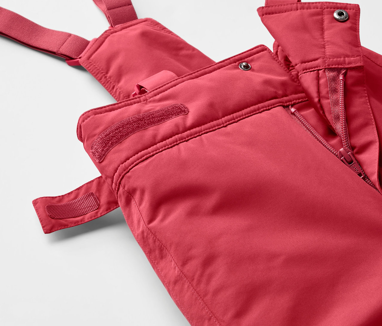 Szczegół czerwonych spodni narciarskich na szelkach z zamkiem błyskawicznym.