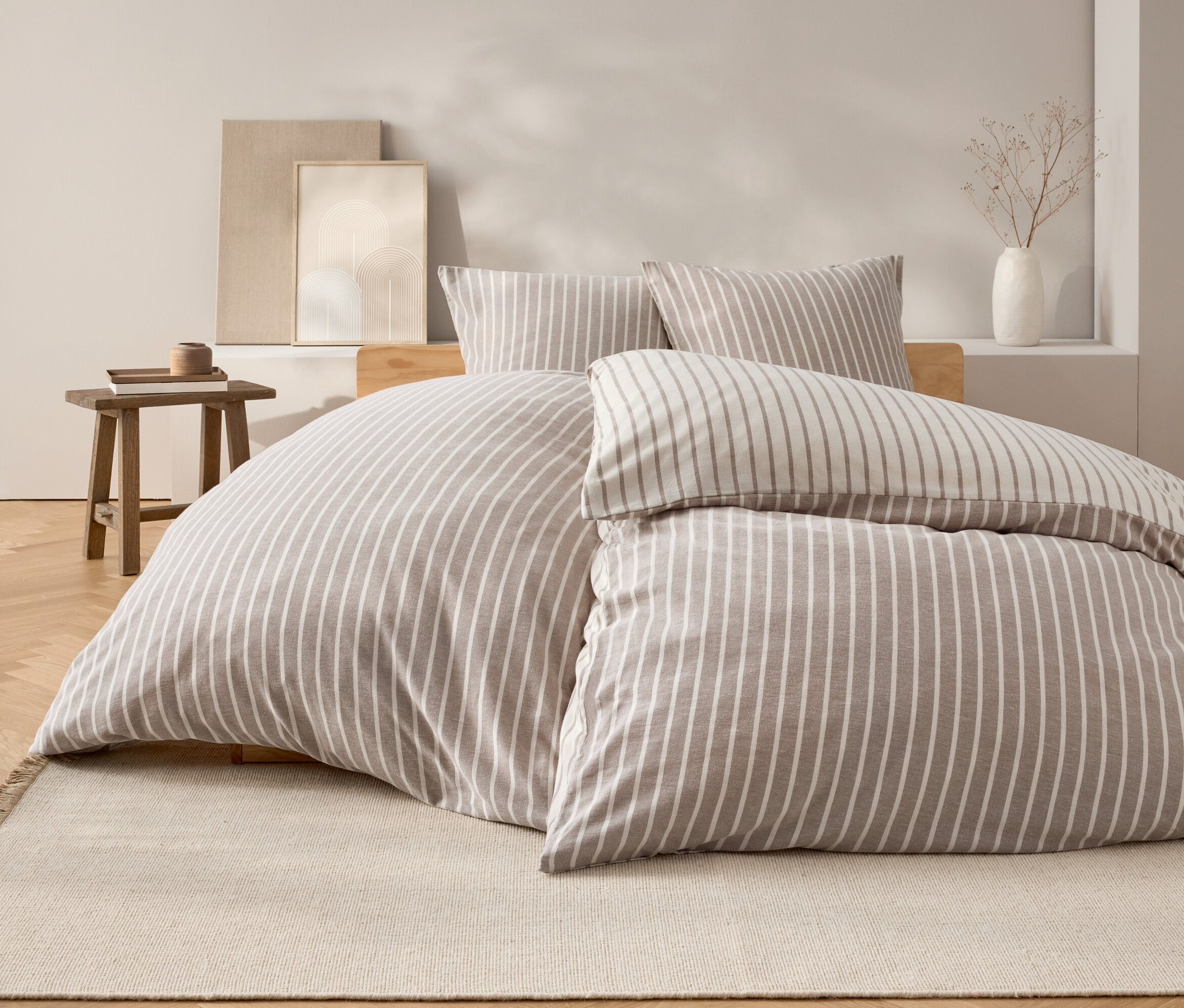 Sypialnia z łóżkiem z pościelą w paski i dwiema poduszkami.