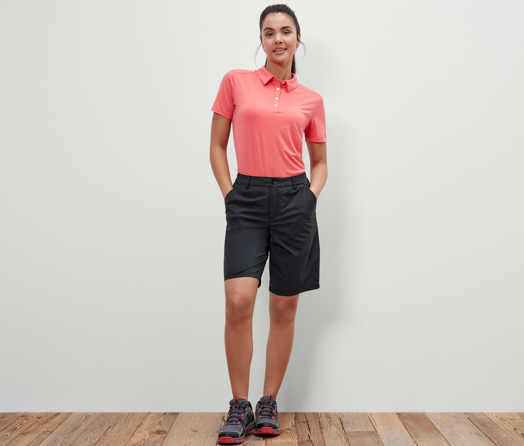Kobieta stoi z rękami w kieszeniach czarnych szortów funkcyjnych z softshellu.